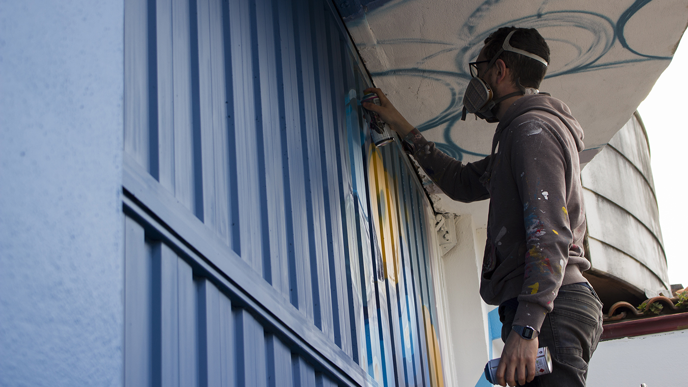 Iñigo Modrego de Ha13estudio, durante la pintura de la fachada del comercio El Globo Feroz.