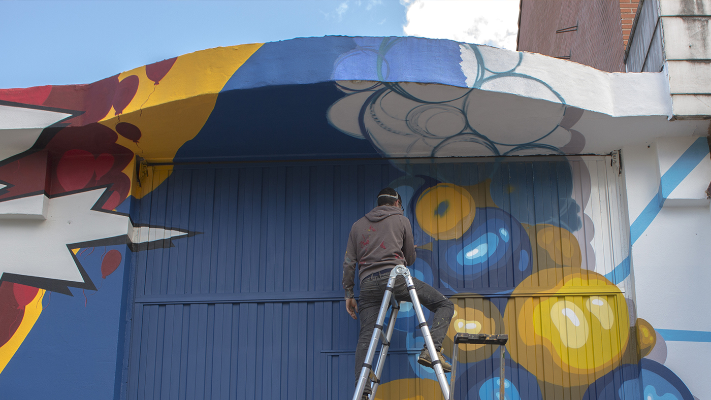 Iñigo Modrego de Ha13estudio, durante la pintura de la fachada del comercio El Globo Feroz.