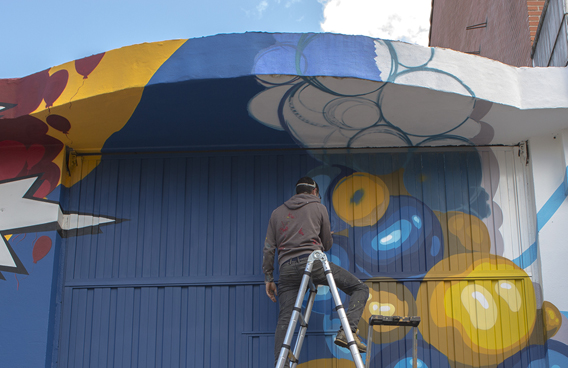 Iñigo Modrego de Ha13estudio, durante la pintura de la fachada del comercio El Globo Feroz.