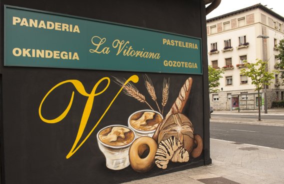 Pintura mural realizada por Ha13estudio en Vitoria Gasteiz, en la pintura se ve un bodegón de panes y bollería