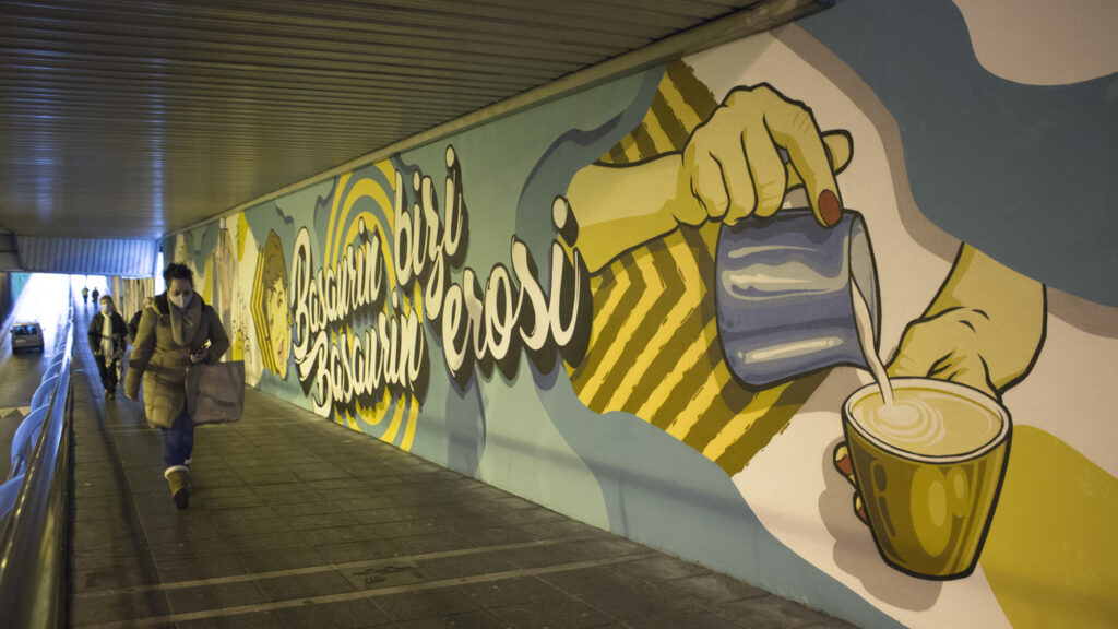 Mural en el que se ven una mano sirviendo un cafe junto alas letras basaurin bizi, Basaurin erosi