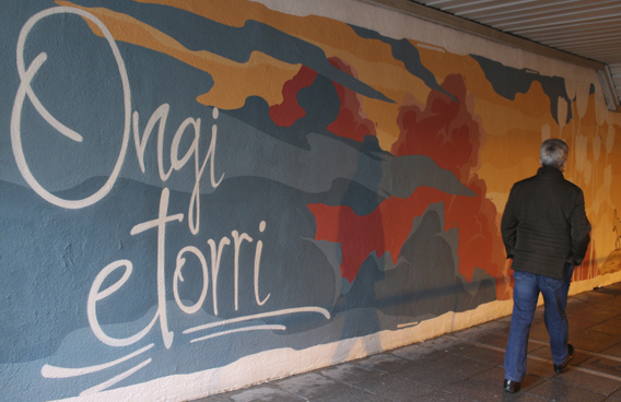 Mural en Basauri en el que aparece la frase Ongi etorri y una persona pasando.