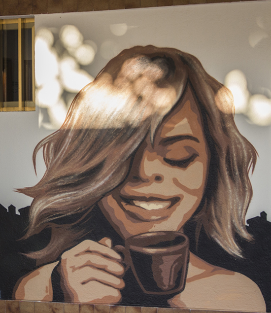 Pintura mural realizada por Ha13estudio de una chica tomando café.