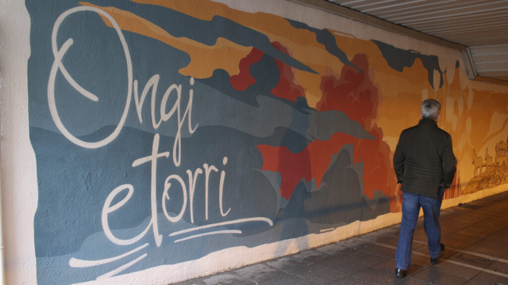 Mural en Basauri en el que aparece la frase Ongi etorri y una persona pasando.